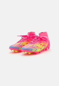 Klare rosa fotballsko med høy topp-design, som har gule og blå aksenter, teksturert overdel og flerfargede stripemønstre.