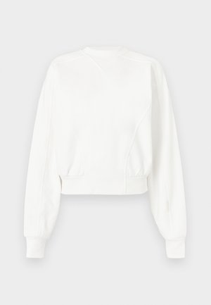 Bela kratka majica z dolgimi rokavi z rebrastimi manšetami, pasom in subtilnim V-obliki šiva blizu okroglega izreza na vratu.