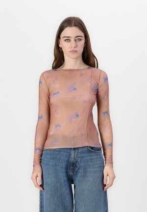 Long-sleeve, sheer top in peach with blue abstract patterns, featuring a crew neckline and visible seam detailing. Paired with denim.