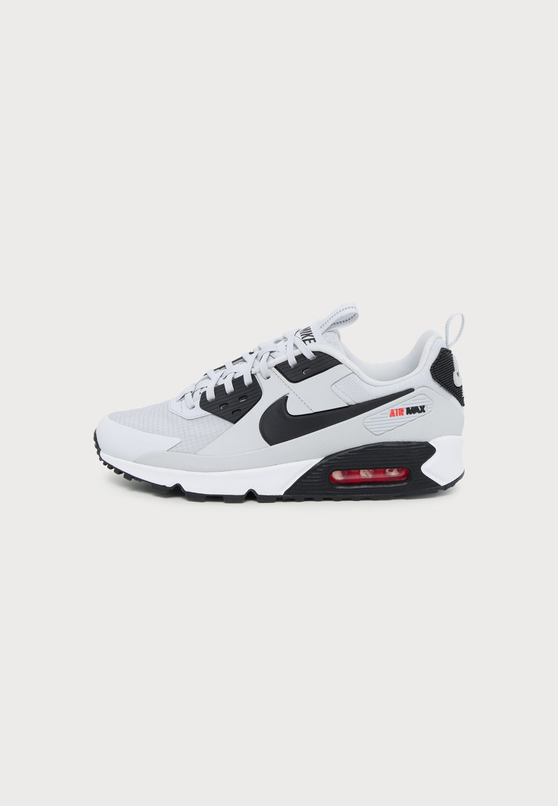 Λευκό και μαύρο παπούτσι Nike Air Max με ορατό κόκκινο αερόσακο στη σόλα, δέσιμο με κορδόνια μπροστά και το σήμα Nike στο πλάι.