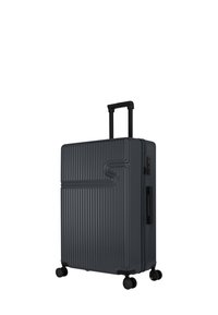 Harde koffer in donkergrijs, met verticale ribbeltextuur, een uitschuifbare handgreep en vier zwarte spinnerwielen voor mobiliteit.