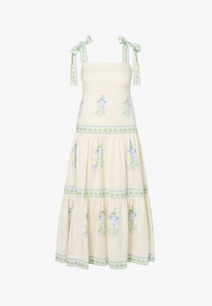 Μακρύ κρεμ φόρεμα με μπλε και πράσινα λουλουδένια σχέδια, με φούστα σε στρώσεις και δεσίματα στους ώμους με το ίδιο λουλουδένιο μοτίβο.