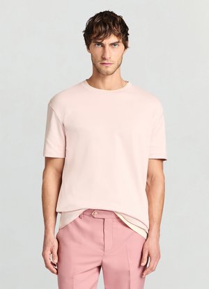 Morbida T-shirt di cotone rosa con scollo rotondo e maniche corte, abbinata a pantaloni sartoriali rosa chiaro. Design semplice e pulito.