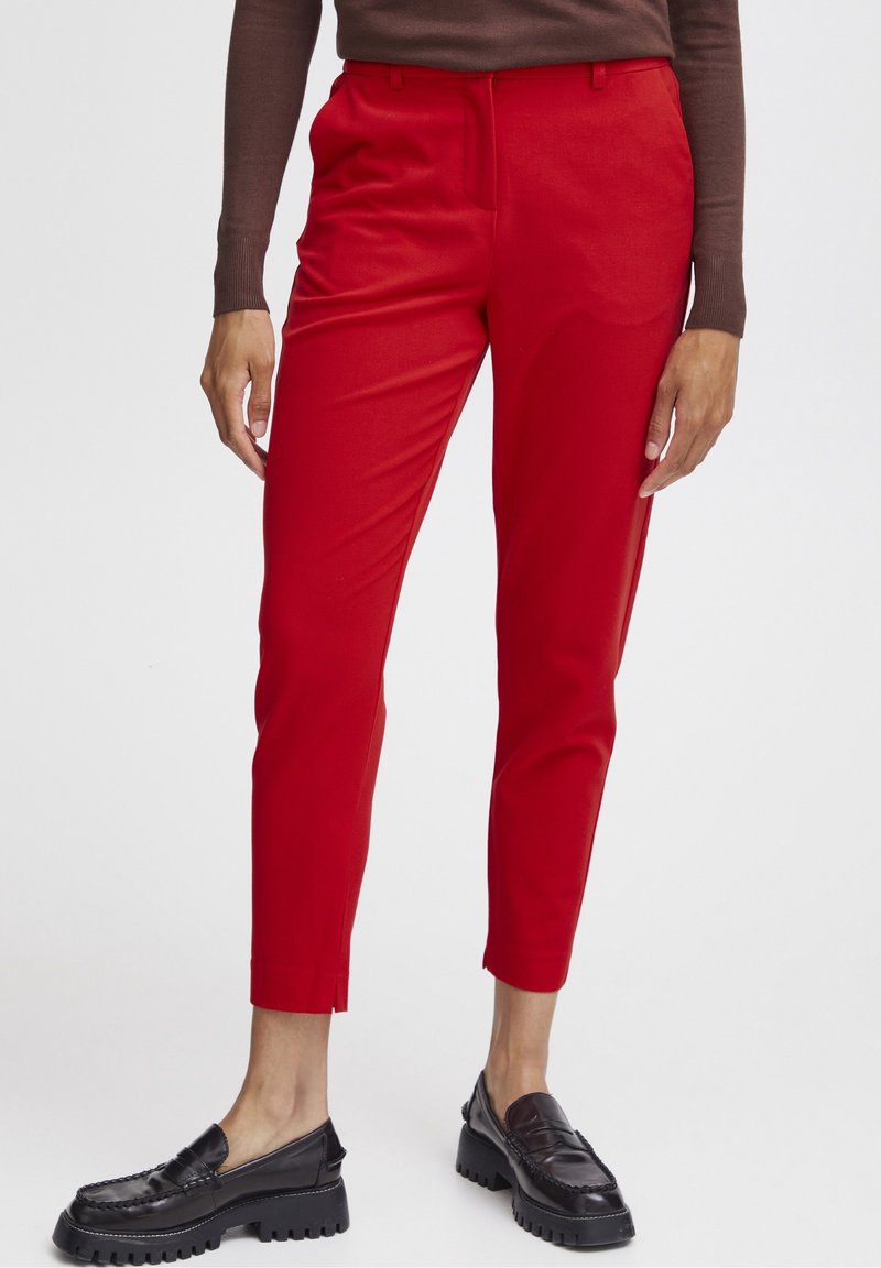 Rode slimfit pantalon met een zachte textuur, zijzakken en splitten in de zoom, gecombineerd met zwarte chunky loafers.
