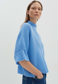 Helles blaues, geripptes Strickpullover mit hohem Kragen und kurzen Ärmeln. Entspanntes Fit und strukturierte Optik. Schlicht und lässig.