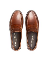Mocasines de cuero marrón con un acabado suave, que presentan detalles de costura y una plantilla acolchada. El interior incluye pequeñas perforaciones para permitir la transpirabilidad.
