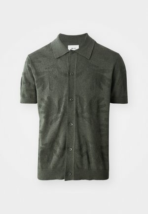 Polo shirt vert olive à manches courtes avec un motif de feuilles texturé, fermeture à boutons et un design de col classique. Tissu tricoté.