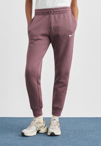 Μπορντό παντελόνι φόρμας από απαλό ύφασμα, με ελαστική μέση, πλαϊνές τσέπες και μικρό λευκό λογότυπο στο αριστερό μπούτι.