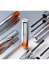 Mascara KIKO Milano avec un tube allongé argenté et rose doré, équipé de têtes de brosse à poils noirs, disposés sur une surface réfléchissante.