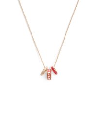 Collier doré comprenant trois pendentifs : un rectangle rouge avec un logo, un pendentif circulaire orné de strass et un accent en forme de fer à cheval rouge.