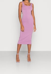 Robe midi lavande ajustée en matière douce et extensible, avec un décolleté rond et de larges bretelles, complétée par des sandales à talons transparentes.