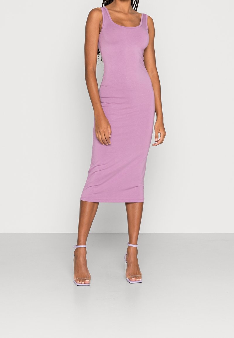 Robe midi lavande ajustée en matière douce et extensible, avec un décolleté rond et de larges bretelles, complétée par des sandales à talons transparentes.