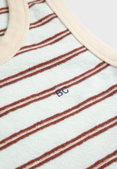 Gros plan sur un col côtelé beige clair et un tissu en coton avec de fines rayures horizontales rouille et de petites lettres "BC" brodées.