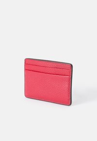 Textured pink leather card holder with smooth black edges, featuring four card slots and a compact, rectangular shape.
