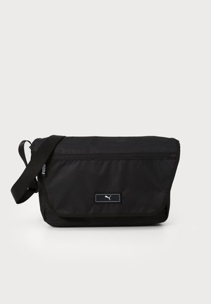 Black messenger bag made of textured nylon with a flap closure, adjustable strap, and a front logo patch.