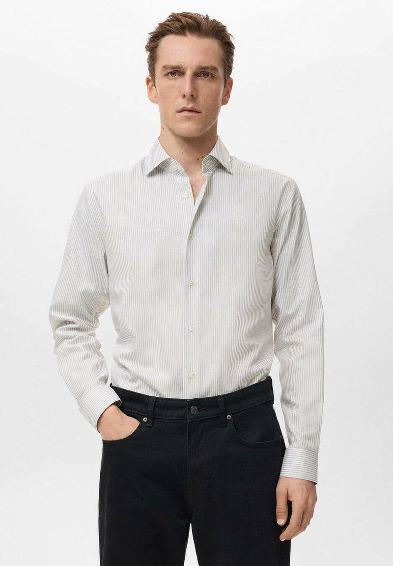 Camisa a rayas gris claro con cuello punta, mangas largas y cierre de botones, combinada con jeans oscuros. Textura de tela suave.