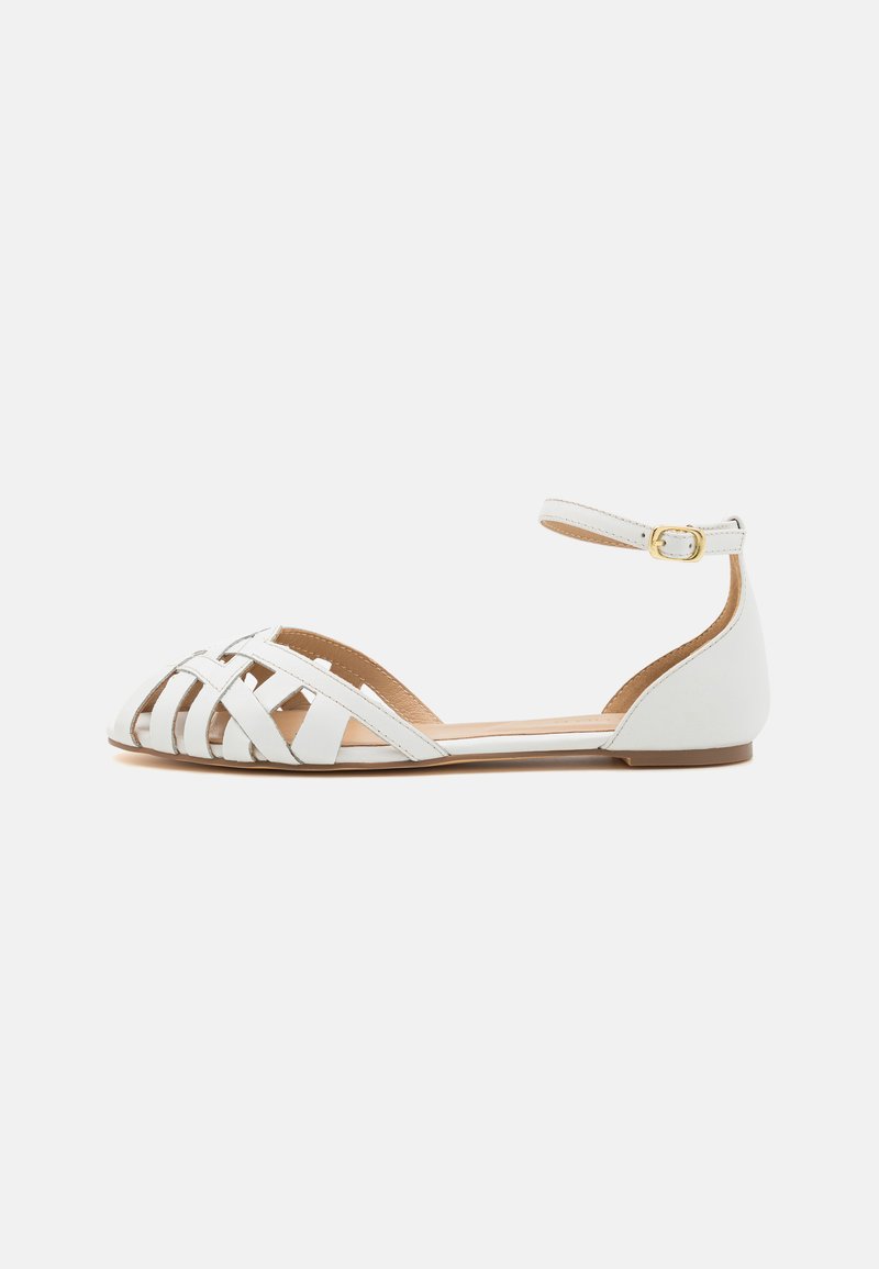 Scarpa piatta bianca con punta affusolata e design della cinghia intrecciata. Presenta una cinghia alla caviglia con una fibbia dorata e una suola piatta. Texture in pelle liscia.