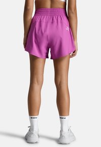 Magenta sportshorts med elastisk talje, har en glat tekstur og hvidt logo-detalje. Shortsene har en løs pasform og går til midten af låret.