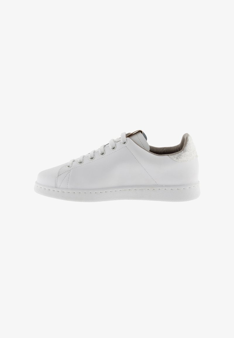 White leather sneaker with a textured back, rounded toe, and flat rubber sole. Features six eyelets and minimalistic design.
