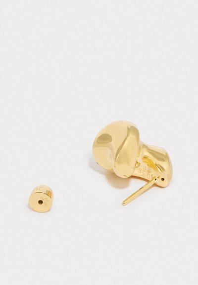 Zelta toņa auskari ar gludu, apaļu dizainu un mazu cilindriskā akcenta elementu. Virsma ir pulēta, sniedzot spīdīgu apdari.