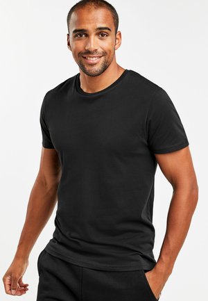 Camisa de algodón negra de manga corta hecha de una tela suave, con un escote redondo, una silueta ajustada y una textura lisa, usada de manera casual.