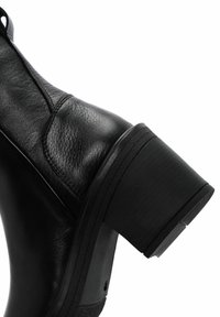 Black leather ankle boot with a textured finish, sturdy block heel, and subtle stitching details. Sleek design, modern silhouette.