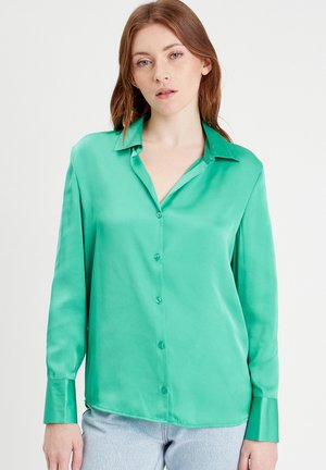 Green satin button-up shirt with a collar, long sleeves, and a smooth texture. Features a slightly curved hem and matching buttons.