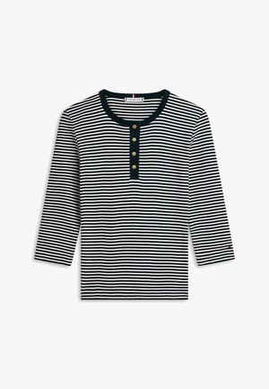 Marineblaue und weiße horizontal gestreifte Langarmshirt mit rundem Ausschnitt und vier goldenen Knöpfen auf einer schwarzen Blende.