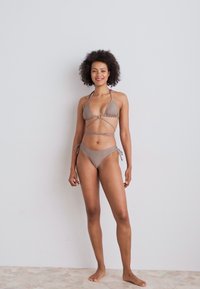 Bruin bikini set met een driehoekige top met bindstrikken en een laag uitgesneden broekje met zijknoopjes, gemaakt van gladde, elastische stof.