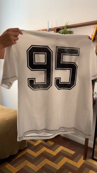 T-shirt branca de manga curta com o número preto "95" impresso nas costas, com costura em contraste e um corte descontraído.