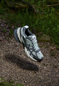 Le sneakers Nike presentano una tomaia in rete grigia con accenti neri e grigi chiari, una suola spessa bianca e grigia, e un'etichetta con il marchio sulla linguetta.