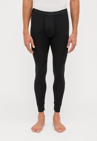 Black leggings made of a smooth, stretchy material. They have a fitted design with a narrow waistband and tapered cuffs at the ankles.