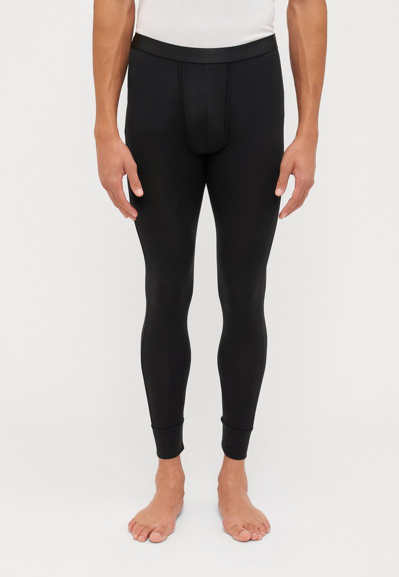Black leggings made of a smooth, stretchy material. They have a fitted design with a narrow waistband and tapered cuffs at the ankles.