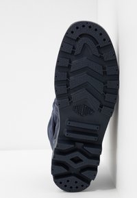 Suela de goma de color azul marino con patrón de textura y logo de PALLADIUM. Construcción robusta con diseño de tacos para mayor tracción.