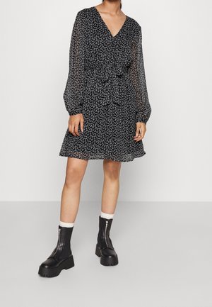 Zwarte bloemige jurk met lange doorzichtige mouwen, V-hals, tailleband en skaterrok. Gestyled met zwarte grove laarzen en witte geribbelde sokken.