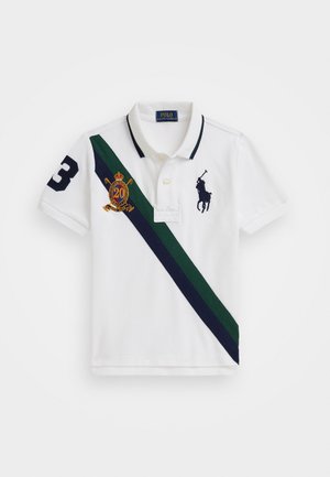 Weißes Poloshirt aus Baumwolle mit einem marineblauen Kragen. Es hat einen diagonalen grünen und marineblauen Streifen, die Nummer "3" und ein gesticktes Logo in Gold und Marineblau.