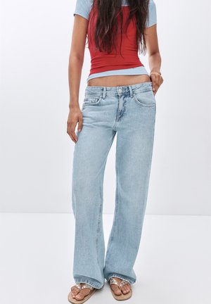 Hellblaue weit geschnittene Jeans aus Denim, mit hoher Taille, fünf Taschen und einer dezenten, ausgewaschenen Textur. Getragen mit einem figurbetonten Oberteil.