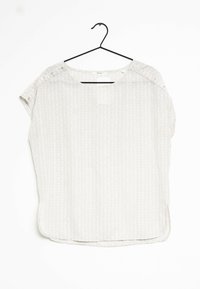 Top grigio chiaro a maniche corte con motivo geometrico, scollatura rotonda e dettagli con bottoni a pressione sulla spalla. Tessuto leggero.