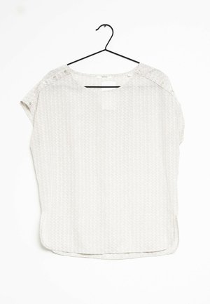 Top corto de manga corta en gris claro con un patrón geométrico, cuello redondo y detalles de botones a presión en el hombro. Tejido ligero.