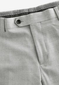 Hellgraue Hose aus strukturiertem Stoff mit schwarzem Knopfverschluss, schmal zulaufenden Beinen und einem klassischen Taillenbunddesign.