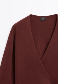 Burgundská vlněná obálková blůza s hlubokým výstřihem do V a dlouhými rukávy, s jemnou texturou a minimalistickým designem.