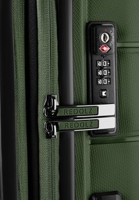 Valise verte texturée avec double fermeture éclair étiquetée Redolz et un cadenas à combinaison TSA noir réglé sur 0-0-0.