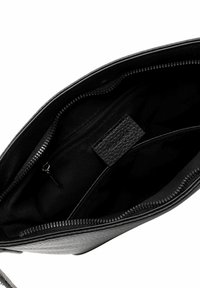 Intérieur d'un sac à main en cuir noir, avec une texture lisse, comportant un compartiment zippé et une poche plate ; design minimaliste sans matériel visible.
