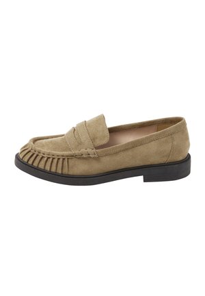 Beige ruskindslæder med folder på tåen, sort sål, lav hæl og slip-on design.