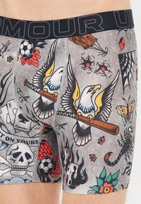Herrenboxershorts mit grauem Grund und bunten, von Tattoos inspirierten Grafiken, darunter ein Adler, Schädel und verschiedene Motive. Mit elastischem Bund.