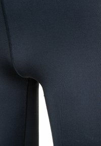 Svarta leggings i stretchigt, slätt tyg med en åtsittande form. Har synliga sömmar och en hög midje-design.
