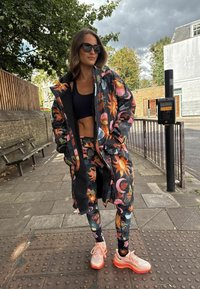 Värvikas lillemustriga mantel musta voodriga. Sobivad säärised ja heleroosad tossud oranžide detailidega. Aksessuaarideks mustad päikeseprillid.