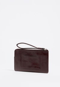 Burgundska usnjena denarnica z teksturirano površino, ima zapestnico in sprednji žep, ki ga varuje zgornji zadrga.