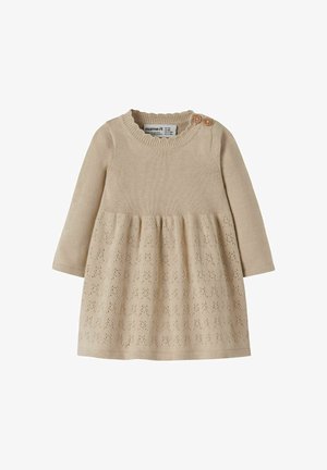 Beige gebreide jurk met een getextureerde bovenkant, lange mouwen en een uitlopende rok met een bloemenpatroon aan de onderrand. Twee houten knopen op de schouder.