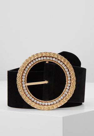 Czarny zamszowy pasek z dużą okrągłą złotą klamrą ozdobioną wzorem skręconej liny oraz rzędem przezroczystych cyrkonii.